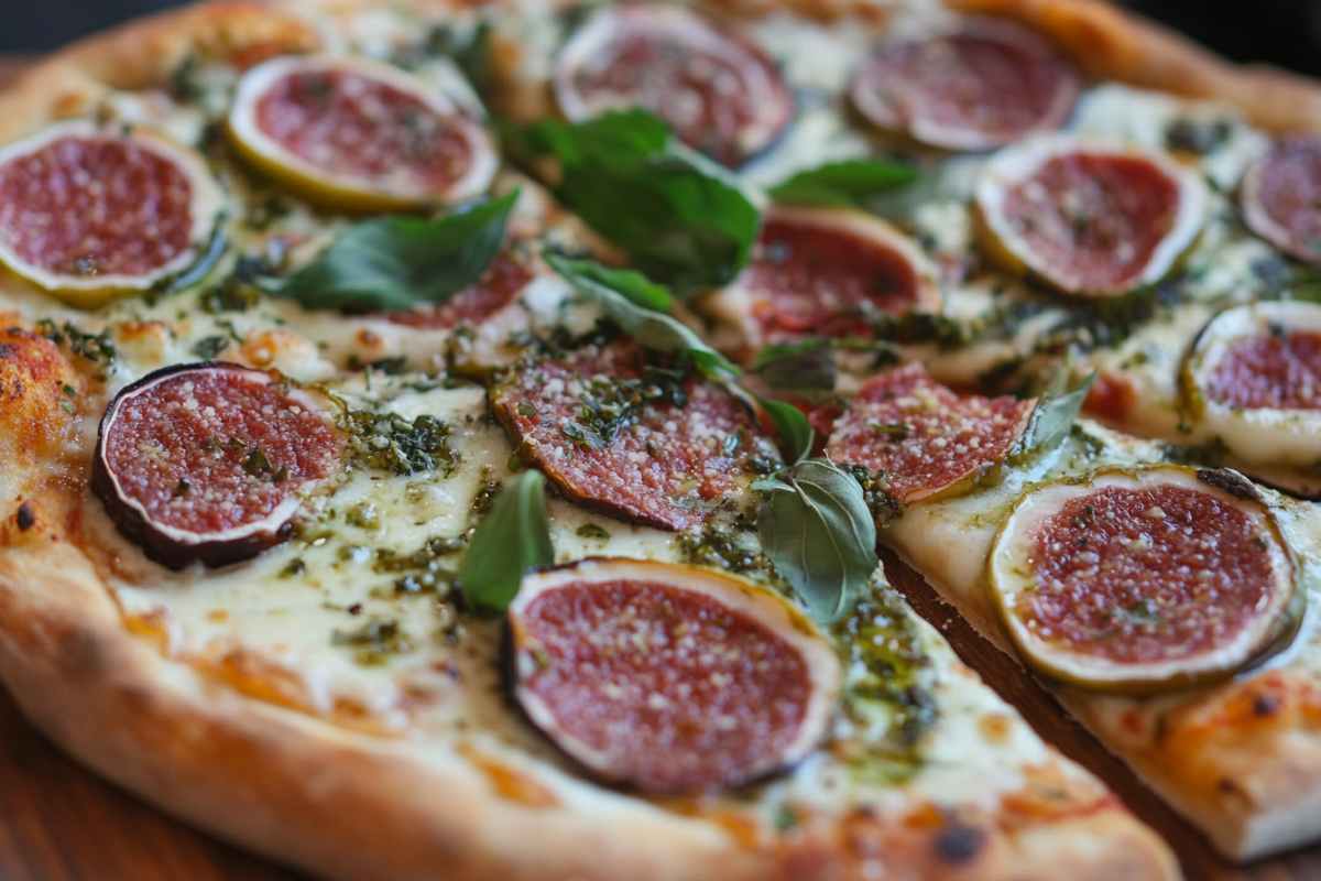 A fig pizza topped with fresh basil leaves and melted cheese